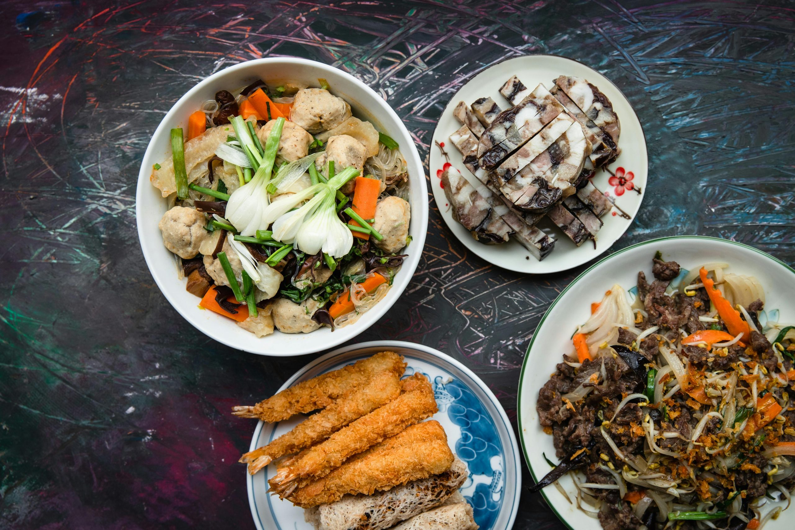 An appetizing top view of a Vietnamese feast featuring assorted meat, vegetables, and noodles.